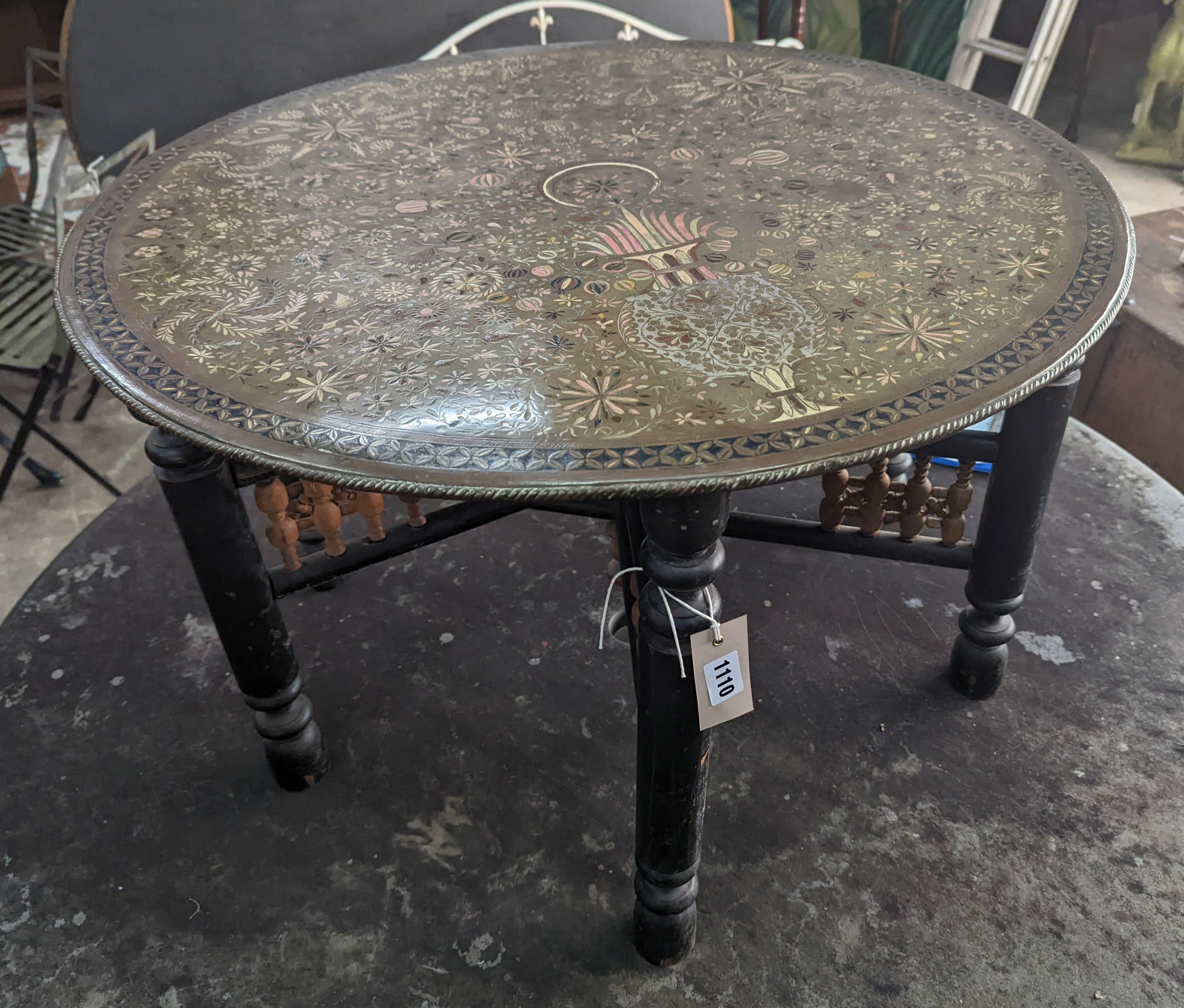 A late 19th century Indian brass and polychrome foliate enamel decorated circular topped occasional table, raised on a turned folding stand, diameter 77cm, height 48cm